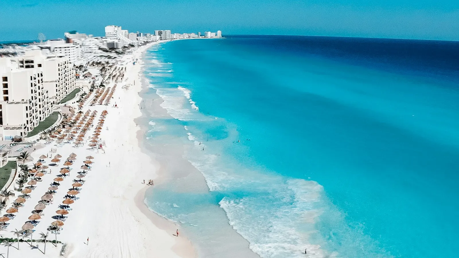 Vista aérea de la playa de arena blanca de la Zona Hotelera de Cancún, con hoteles, sombrillas y mar turquesa